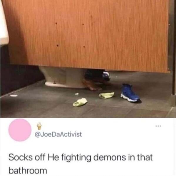 A photo shows a person's feet and legs partially hidden under a wooden bathroom stall door, with one blue sneaker and two…