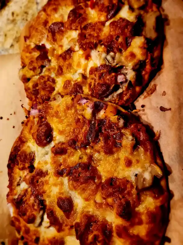 A close-up photo of two slices of cheesy pizza with pepperoni and onions on parchment paper. The text overlay reads 'i'm not…