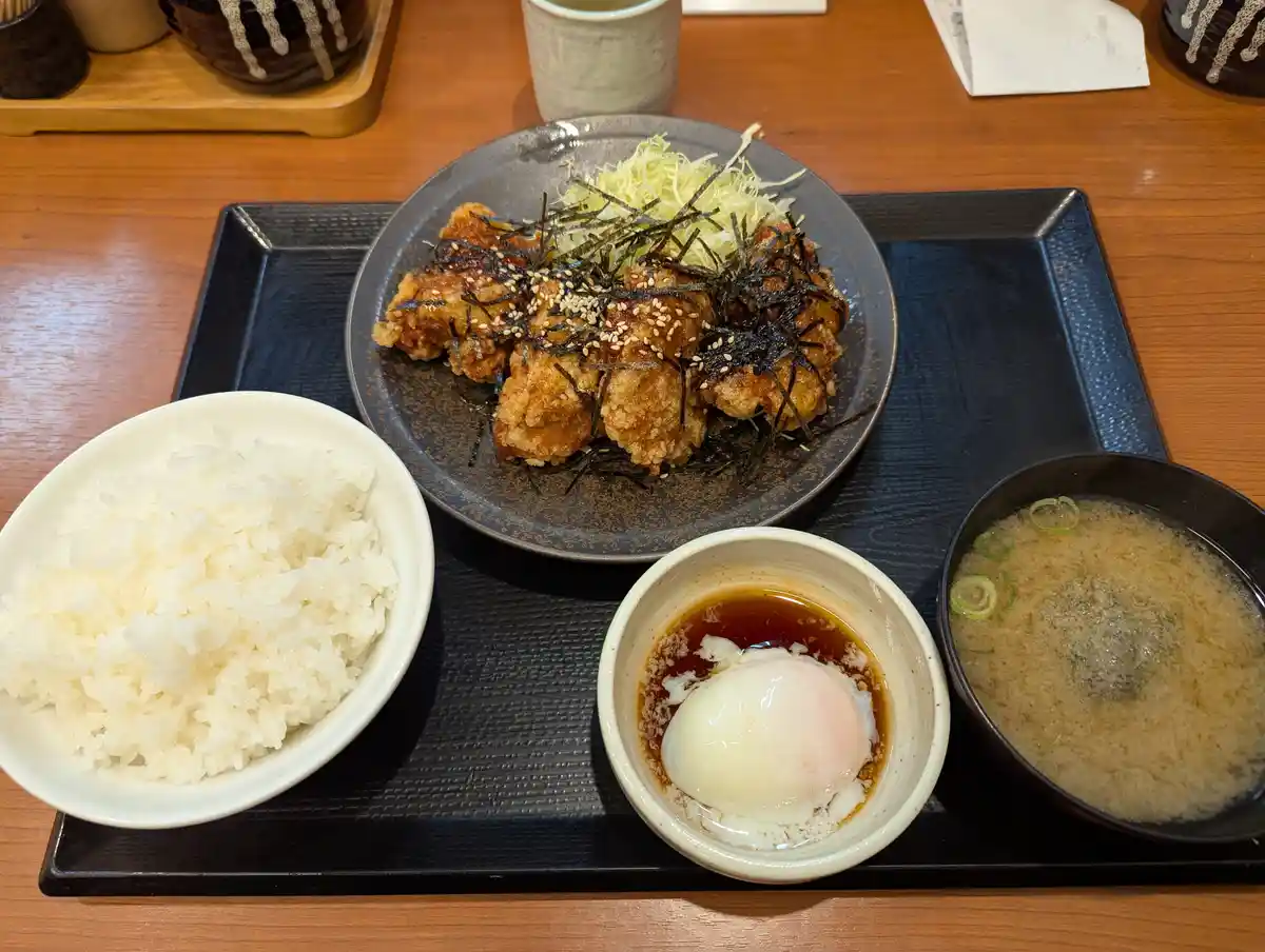 a japanese meal featuring fried chicken katsu on a plate with shredded cabbage and seaweed, served with white rice, a bowl…