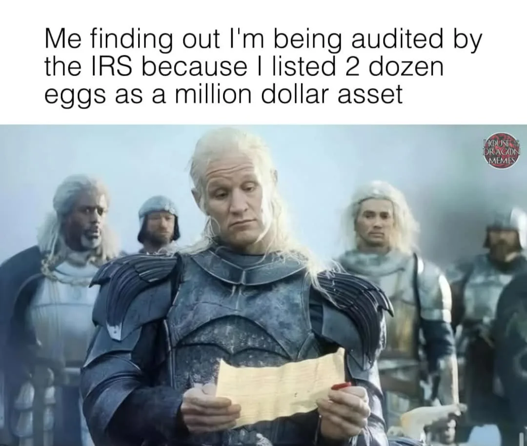 A man in dark armor with long white hair, holding a scroll, looks down with a shocked and dismayed expression. Behind him…
