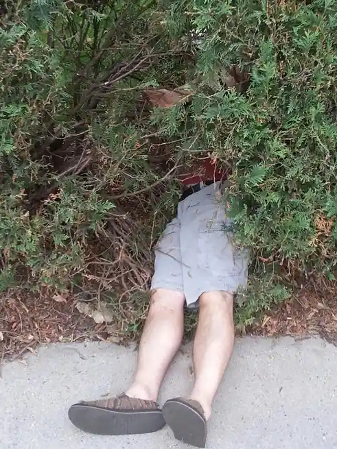 a person is lying on their back on a concrete sidewalk with their legs visible, wearing shorts and sandals, while their…