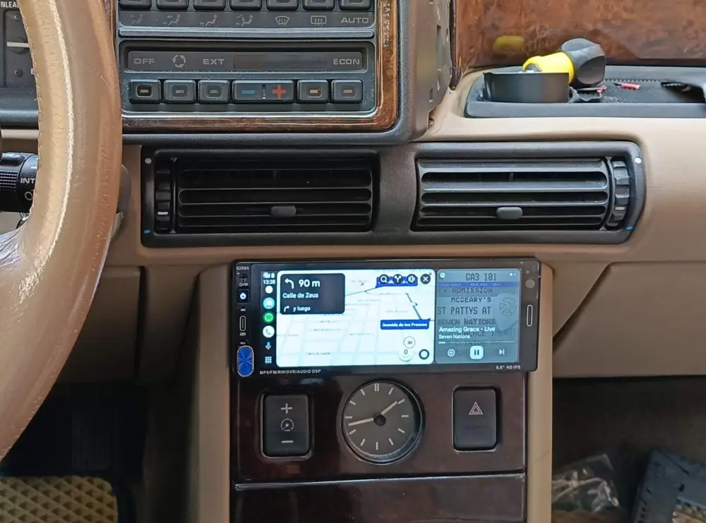 A car dashboard shows a GPS navigation screen with a split view: the left side displays '90 m Calle de Zeus y luego' (90…
