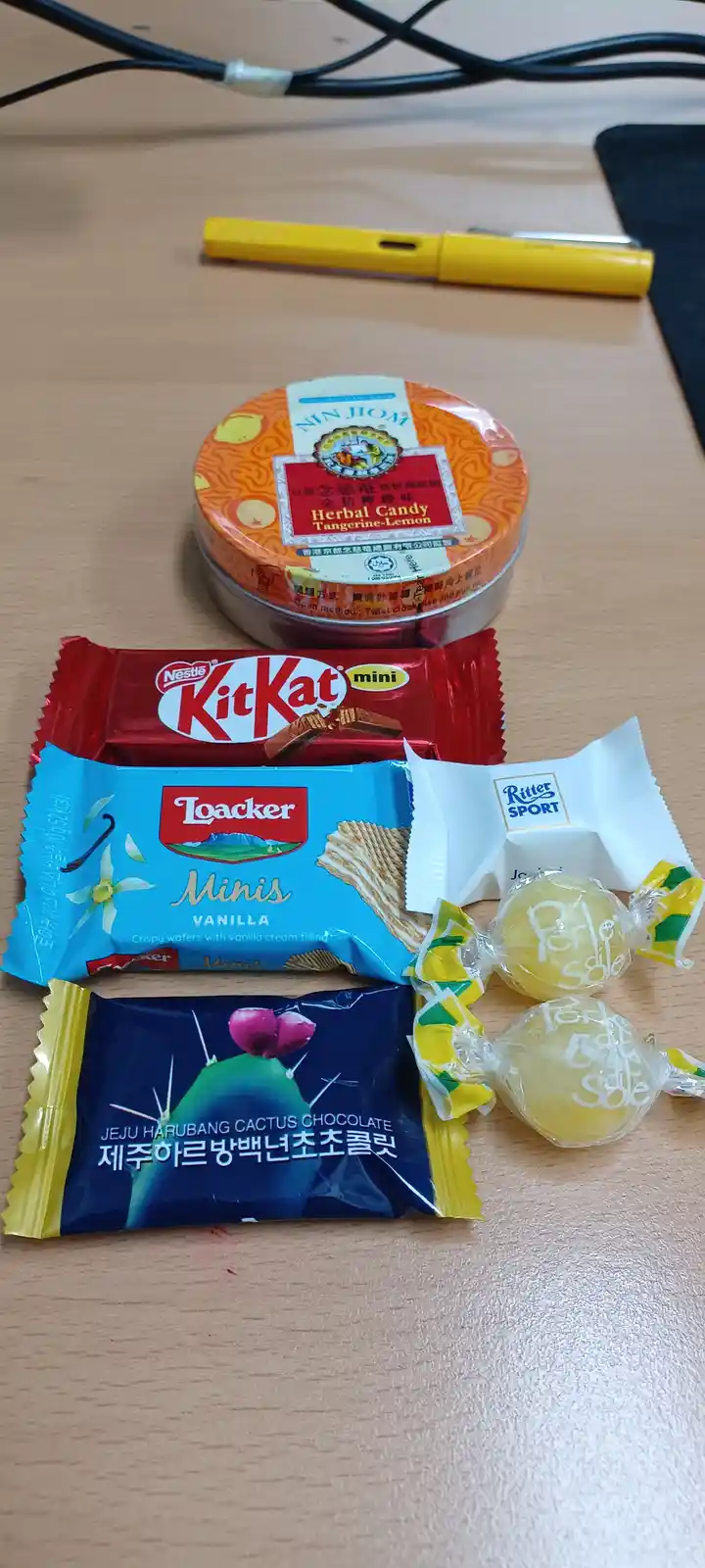 A collection of assorted candies and snacks including a KitKat mini, Loacker Minis Vanilla, Ritter Sport chocolate, Perle…