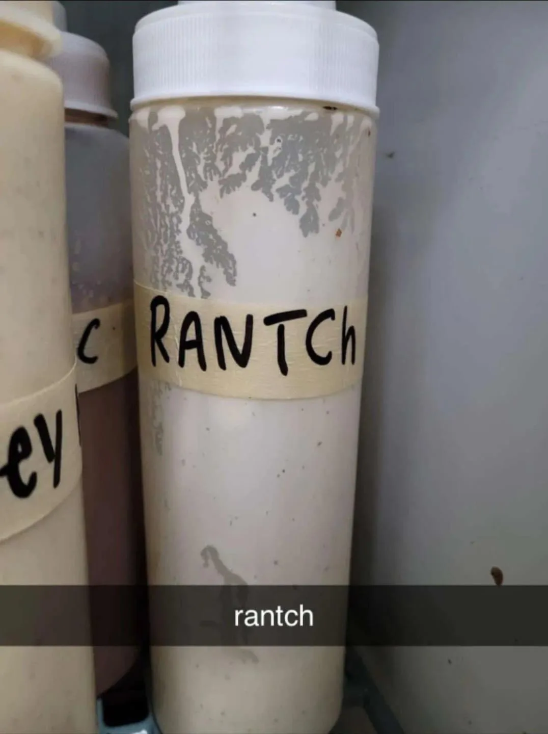 A close-up photo shows a white squeeze bottle with a handwritten label that reads 'RANTCH', which is a misspelling of…