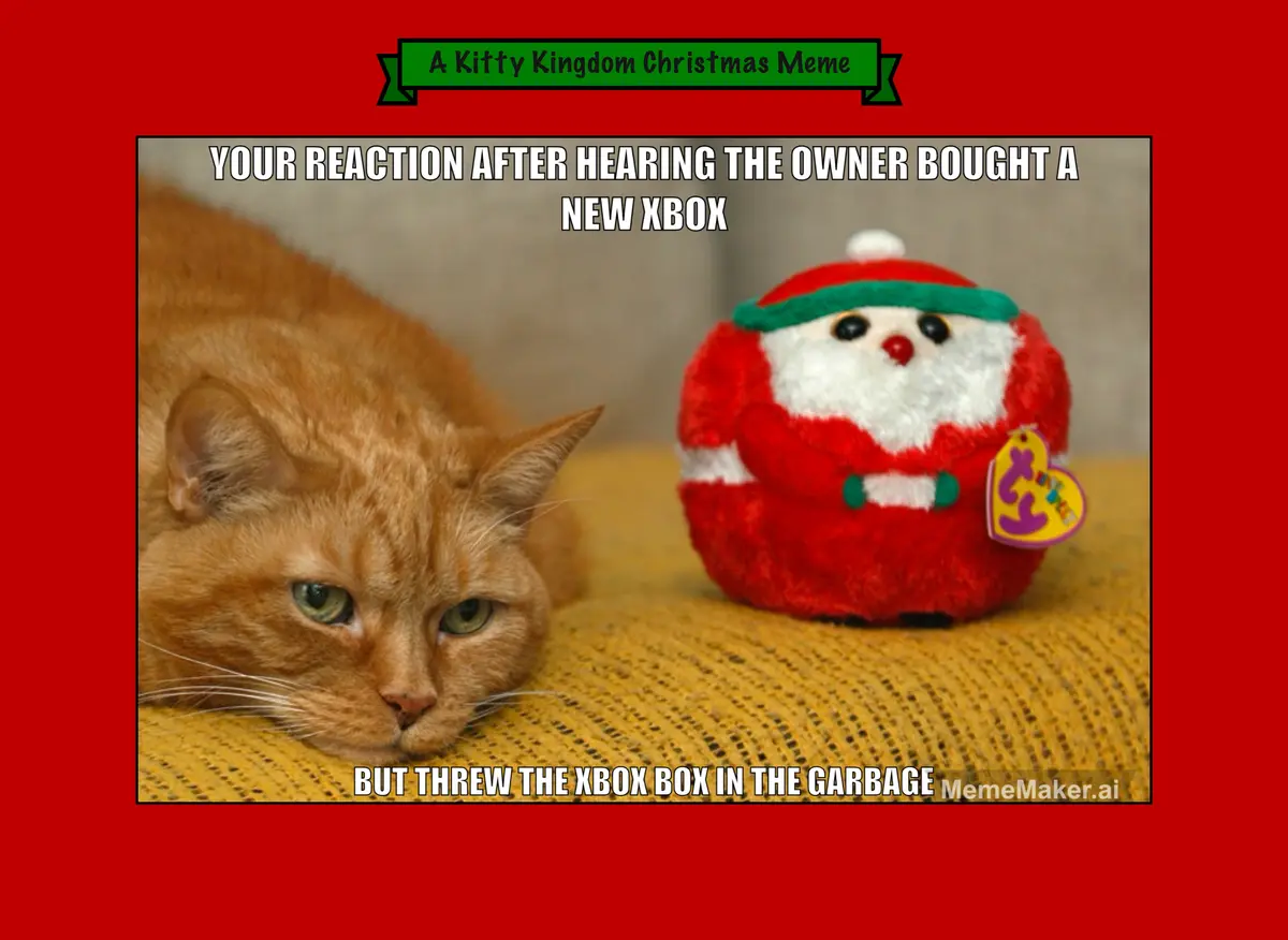 An orange tabby cat with a bored, unimpressed expression lies on a yellow textured surface next to a small, round, red plush…
