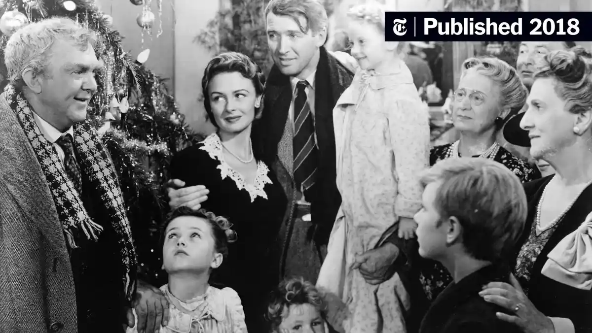 A black-and-white photo of a family gathered around a decorated Christmas tree, with a young girl looking up at an older man…