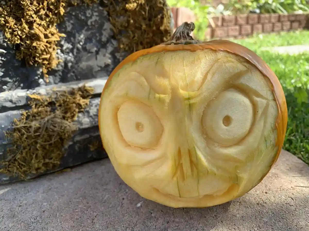 A close-up photo shows a pumpkin with its top carved into a face, featuring large circular eyes with small holes in the…