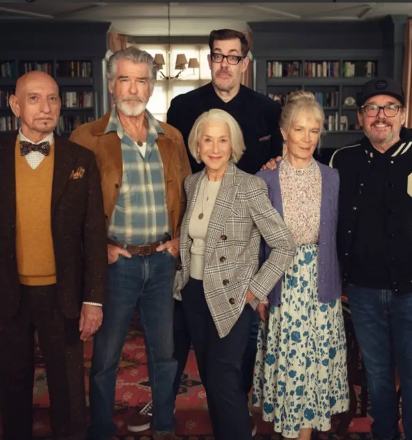 A group photo of six actors, including Pierce Brosnan, Helen Mirren, and others, posing together in a room with bookshelves…