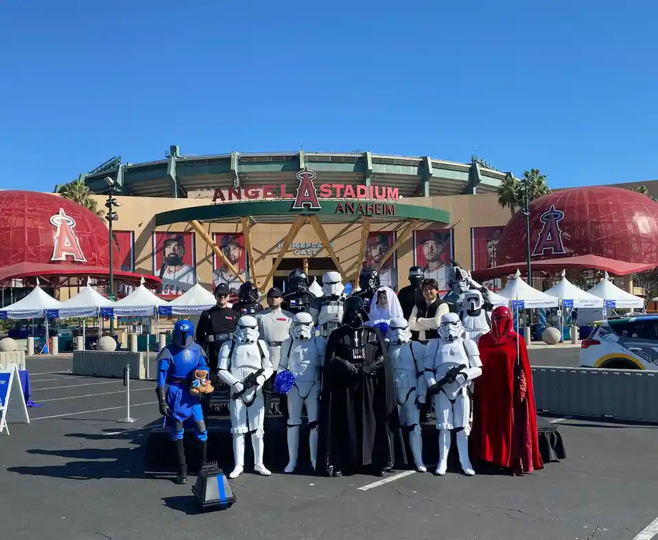 A group of people dressed as Star Wars characters, including Darth Vader, Stormtroopers, and other figures, pose for a photo…