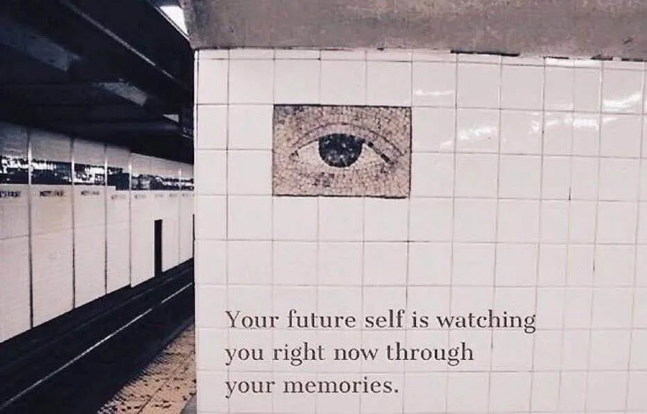 A subway station wall covered in white tiles features a mosaic of an eye. Below it, text reads: 'Your future self is…