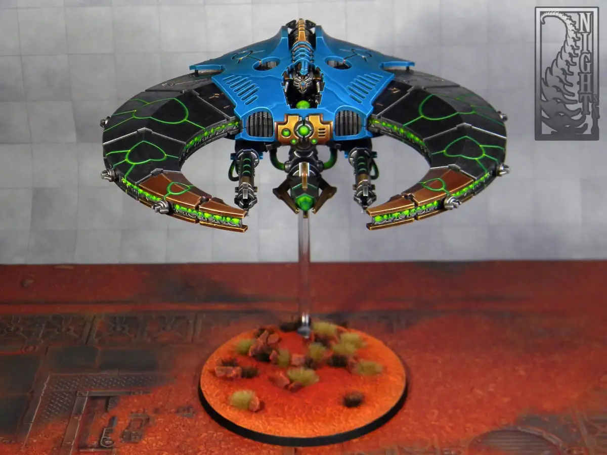 A highly detailed, painted miniature of a blue and black futuristic spaceship with glowing green circuitry, mounted on a…