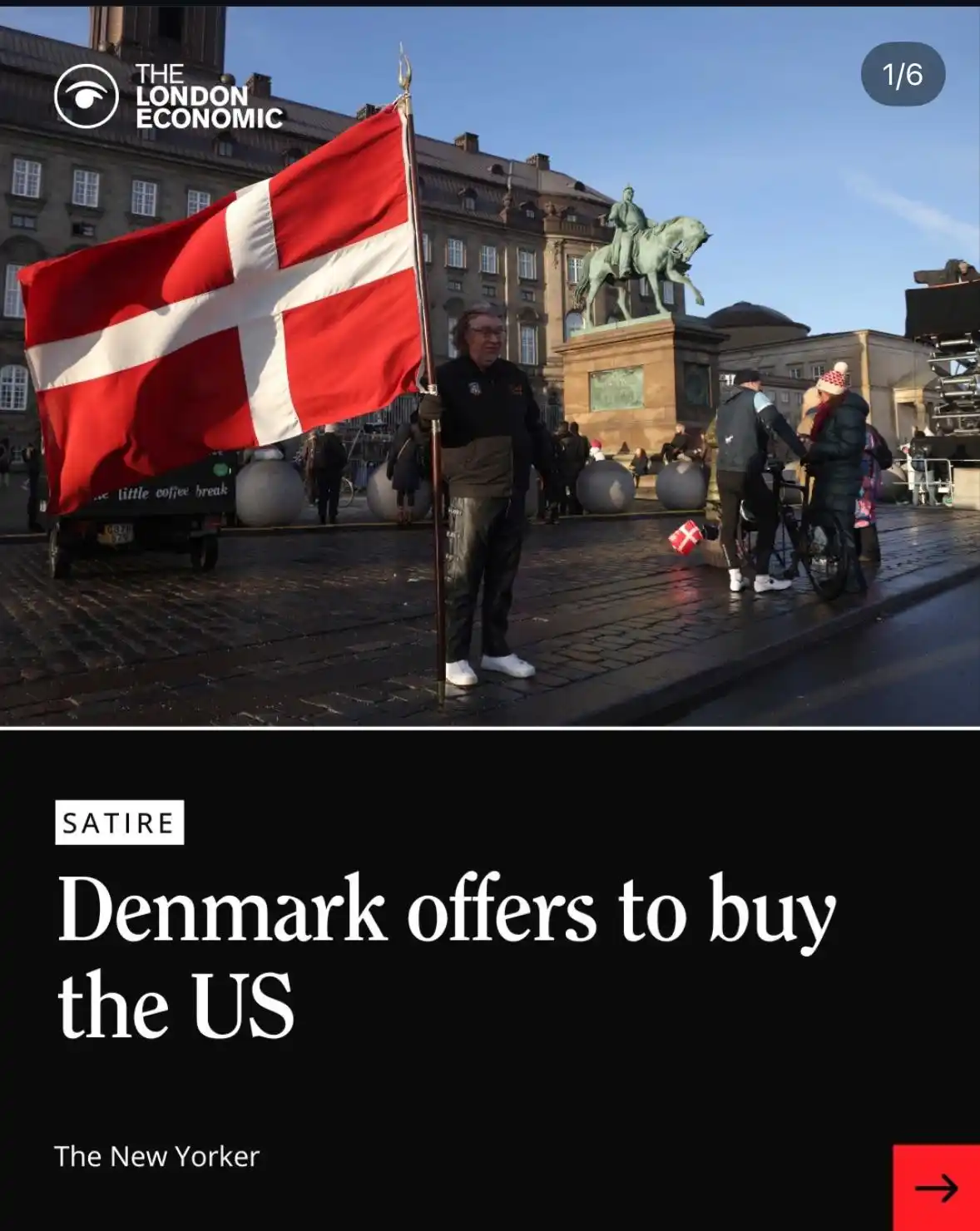 A man stands in a public square holding a large Danish flag, with a historic building and a statue of a mounted figure in…