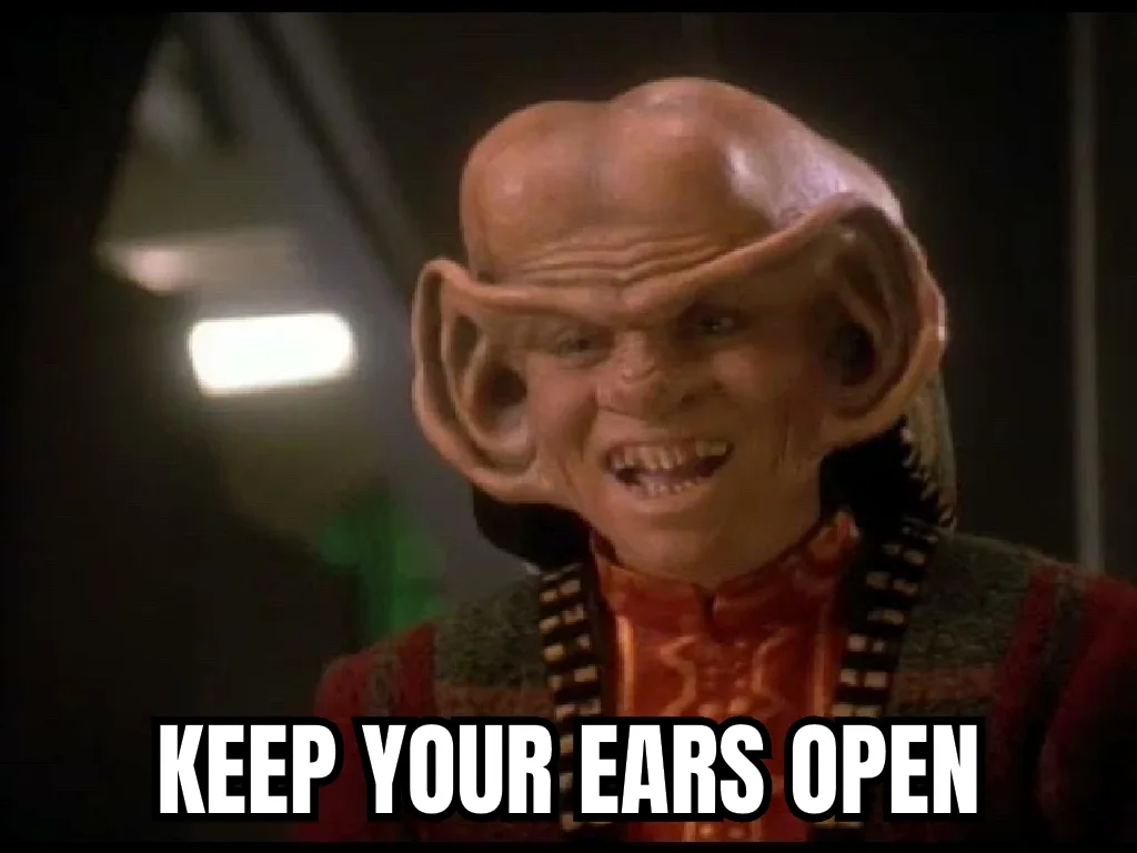 A close-up of a bald, alien character with large, prominent ears and a menacing expression, wearing a red and patterned…