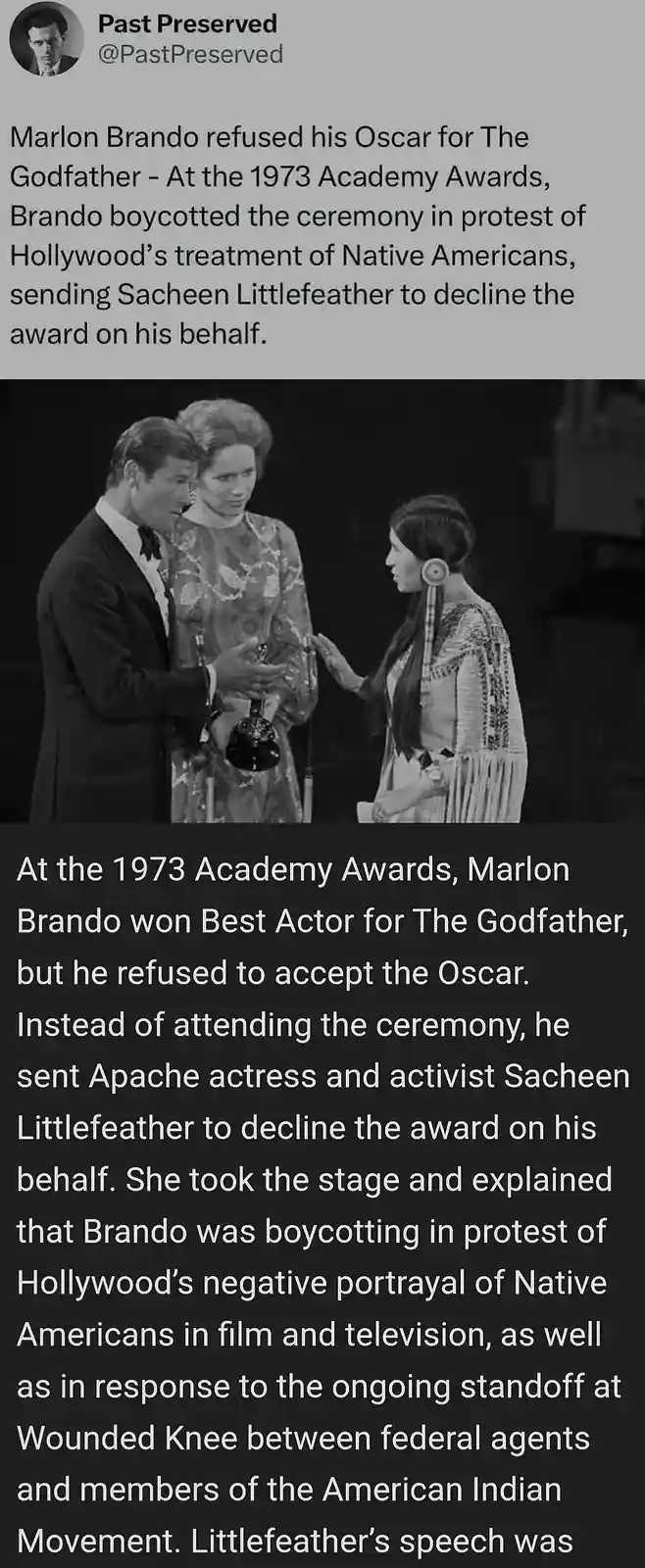 A black-and-white photo from the 1973 Academy Awards shows Marlon Brando in a tuxedo holding an Oscar, standing beside a…