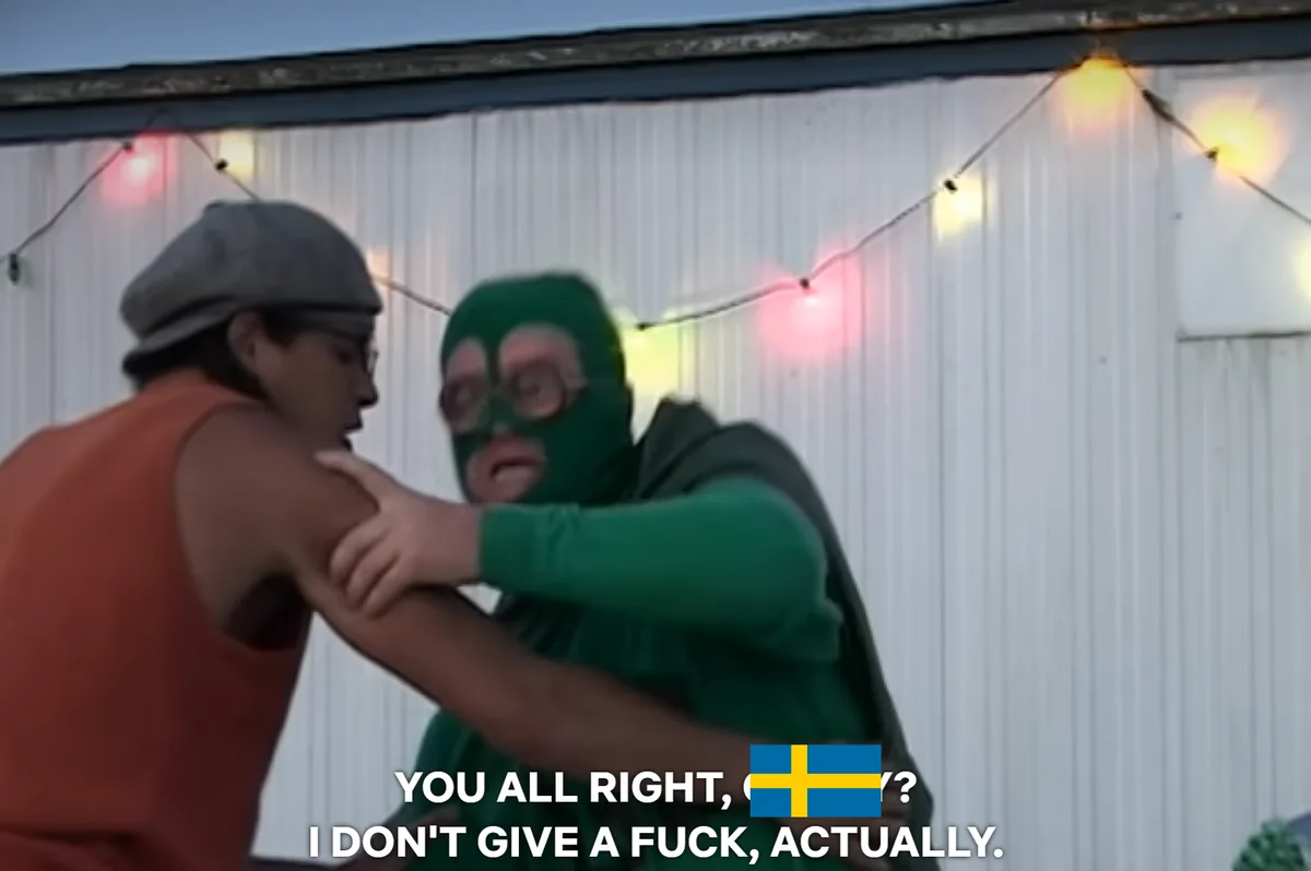 Two men are in a physical altercation outdoors; one wears a green balaclava and glasses while grabbing the other's arm, who…