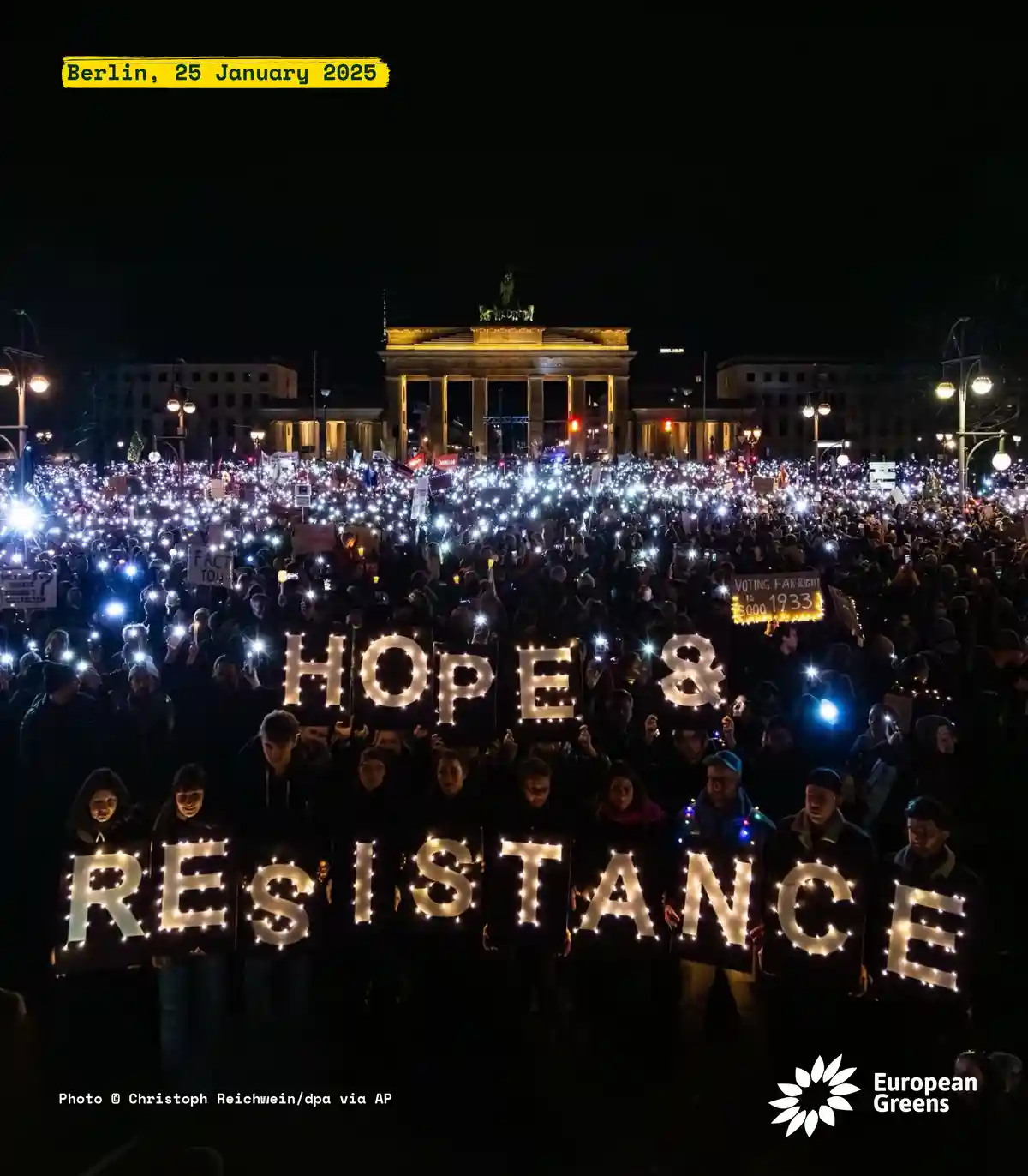 A large nighttime protest in Berlin, Germany, with thousands of people holding up lit signs spelling 'HOPE & RESISTANCE' in…
