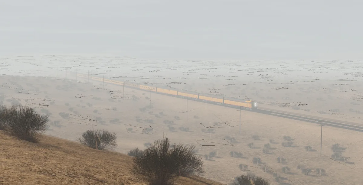 A long yellow train travels across a vast, hazy desert landscape with sparse vegetation and power lines. The image has a…