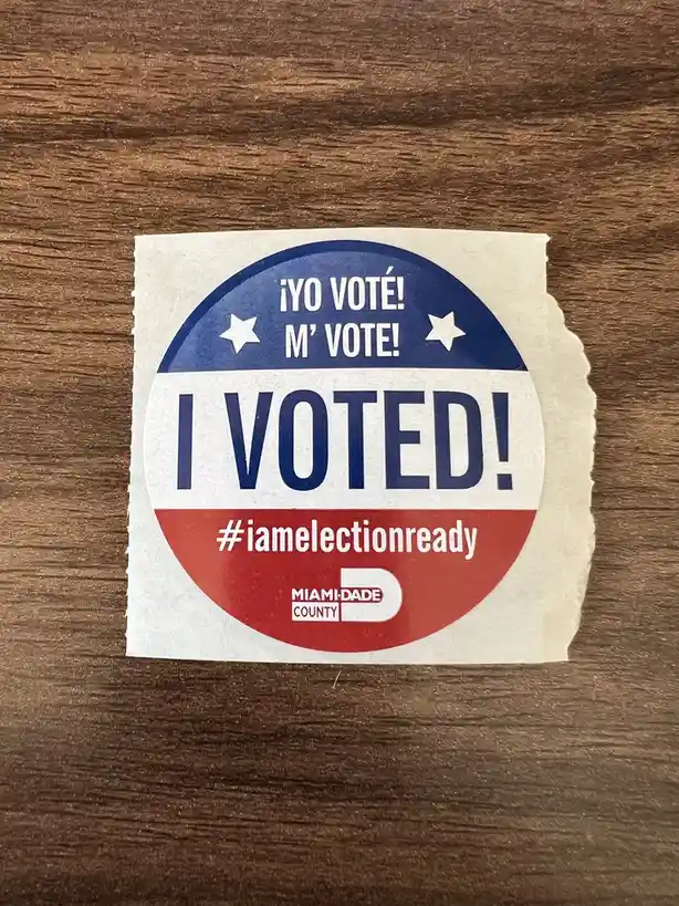 A circular 'I VOTED!' sticker from Miami-Dade County, featuring red, white, and blue sections with stars, is placed on a…