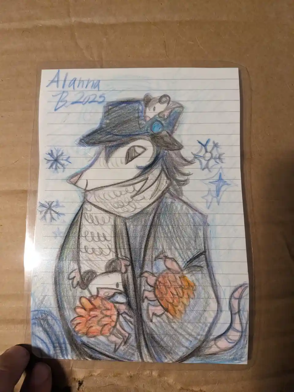 A hand-drawn colored pencil illustration on lined notebook paper shows an anthropomorphic animal character with a wide grin…