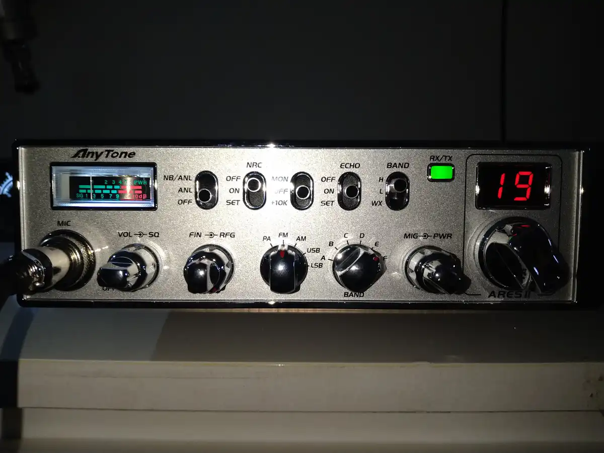 A close-up of an AnyTone ARES II radio transceiver with a red digital display showing the number 19, surrounded by various…