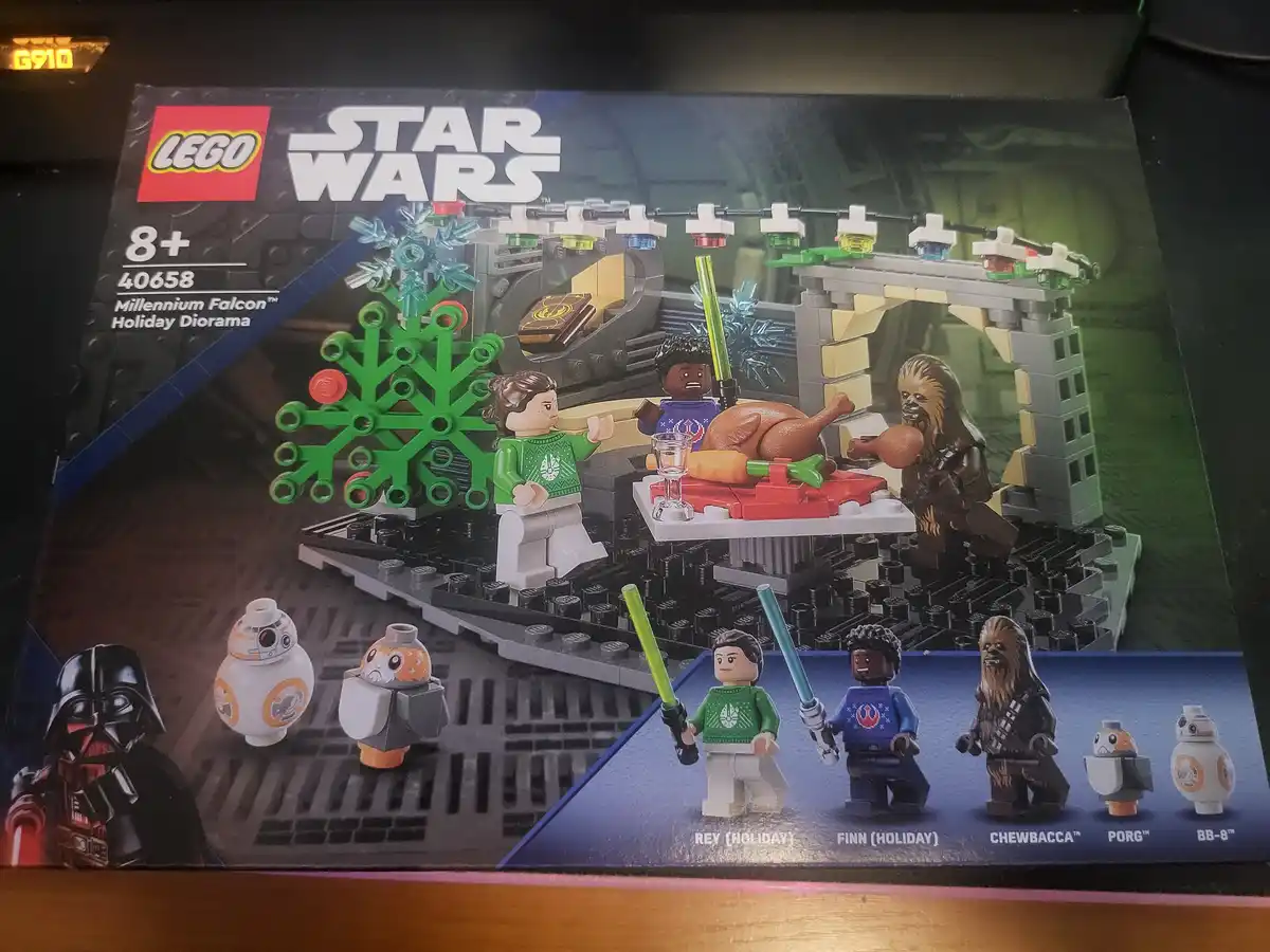 The image shows a LEGO Star Wars box for set 40658, 'Millennium Falcon Holiday Diorama,' featuring LEGO minifigures of Rey…