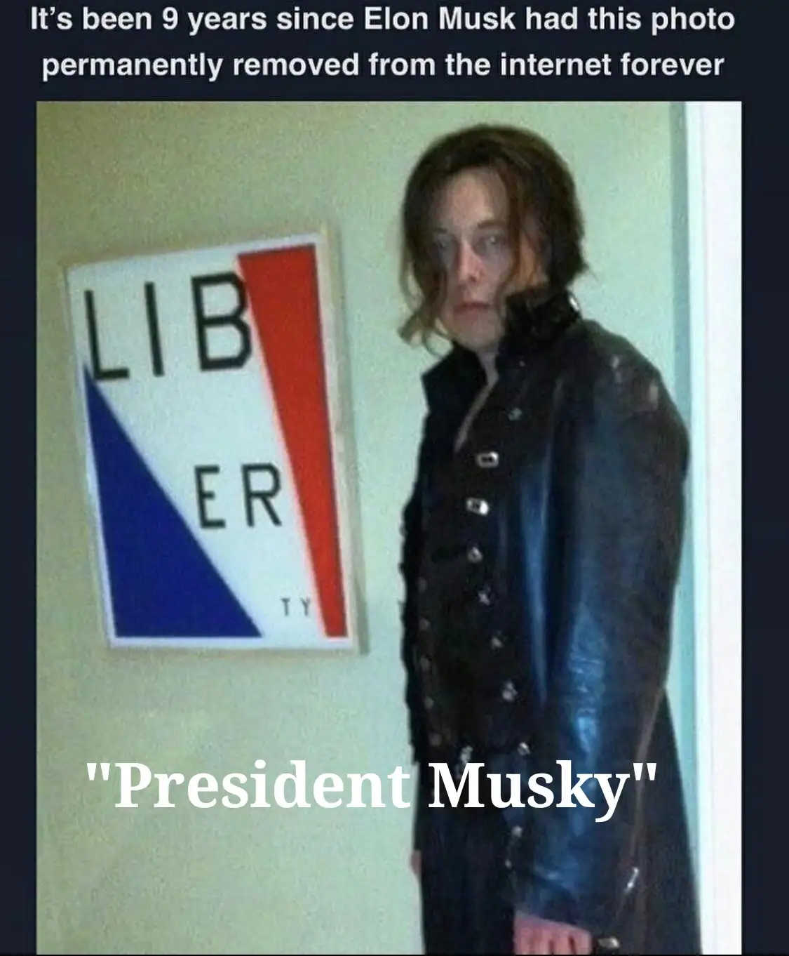 A person with long hair and a black leather jacket stands beside a framed sign that reads 'LIBERTY' in black letters on a…