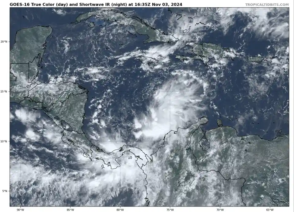A satellite weather image from GOES-16 shows a large, swirling storm system over the Caribbean Sea near Central America. The…