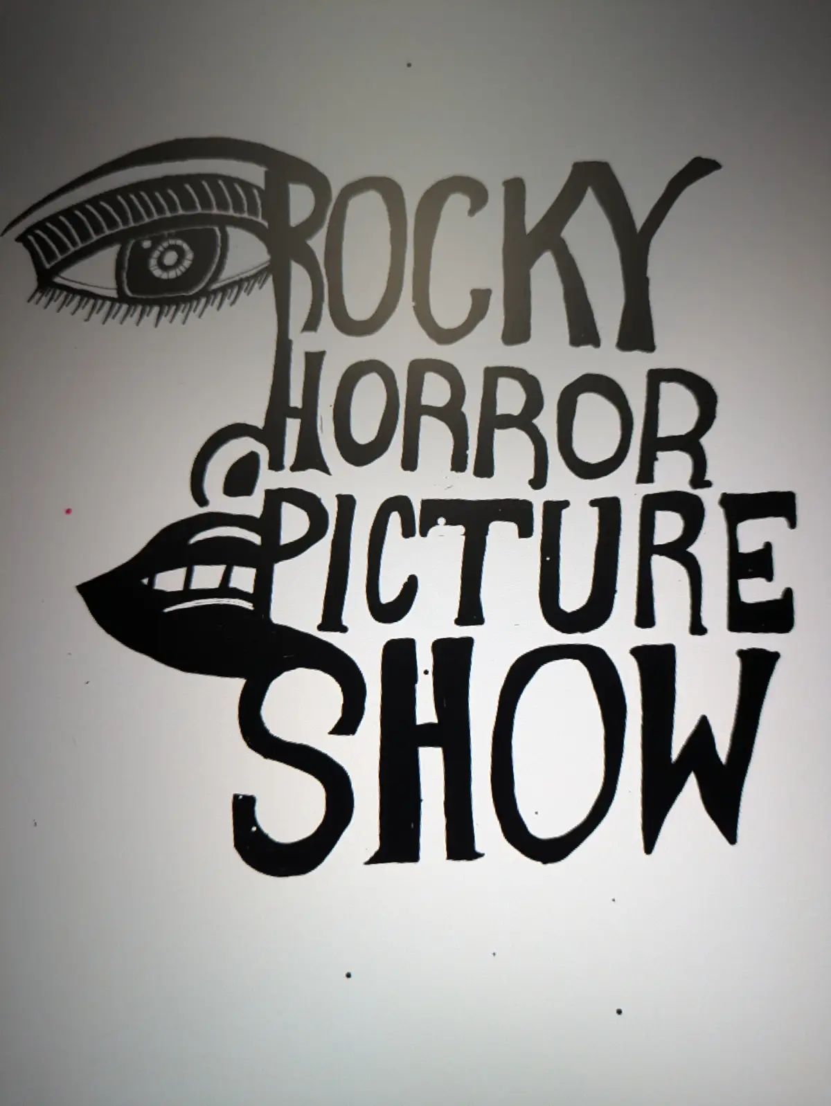 A hand-drawn black-and-white image features the iconic title 'ROCKY HORROR PICTURE SHOW' in stylized lettering, with an eye…