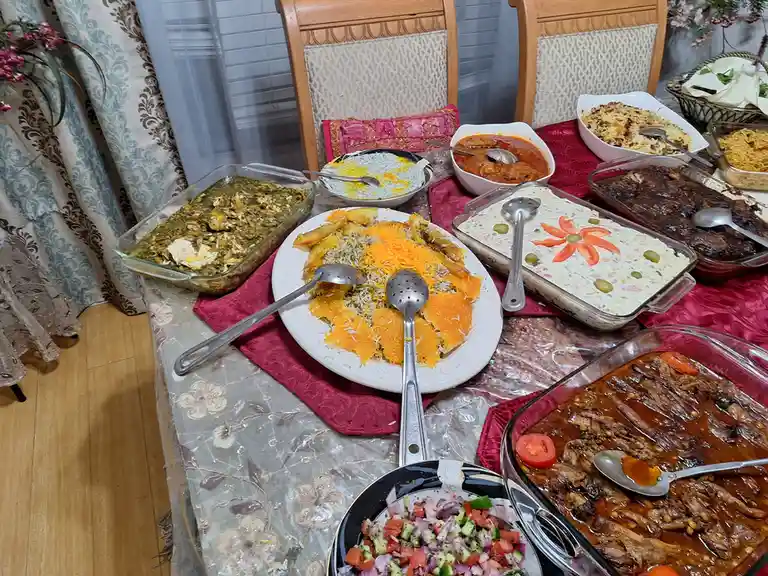 A lavish spread of multiple Persian-style dishes, including rice with orange slices, stew, salad, and various sauces…