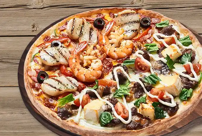 a close-up photo of a heavily loaded pizza on a wooden board, featuring grilled chicken, large shrimp, black olives, cherry…