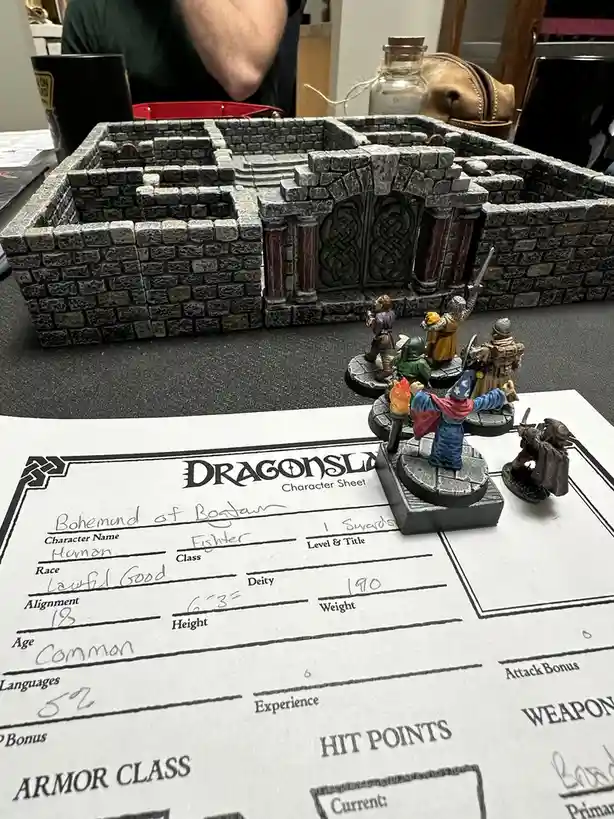 A tabletop role-playing game scene featuring miniature fantasy figures on a stone dungeon map, with a 'Dragonlance Character…