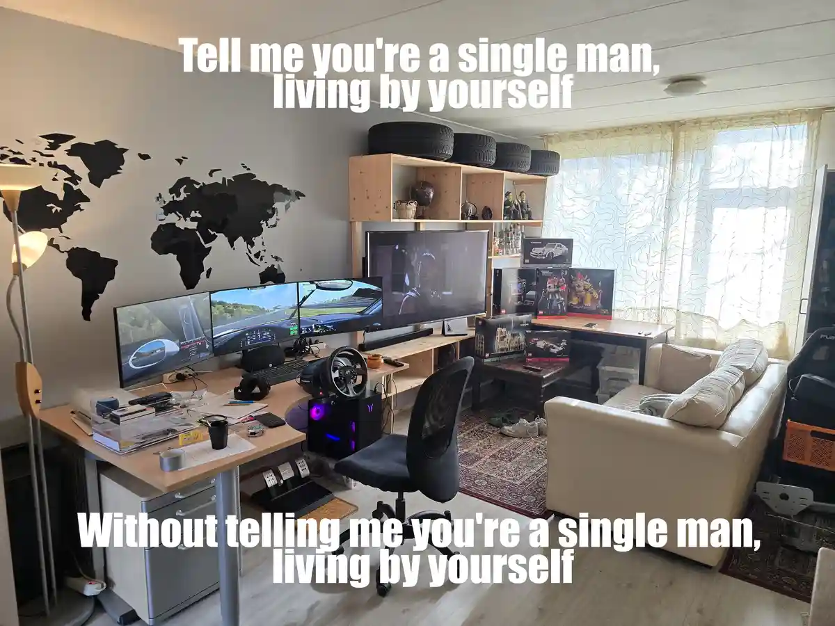 A room filled with gaming equipment, including multiple monitors, a racing wheel, and a large TV, alongside a couch, shelves…