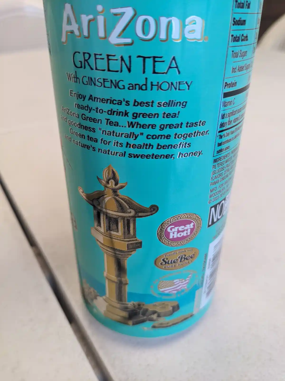 A close-up of an AriZona Green Tea with Ginseng and Honey beverage can, showing its turquoise label with product name…