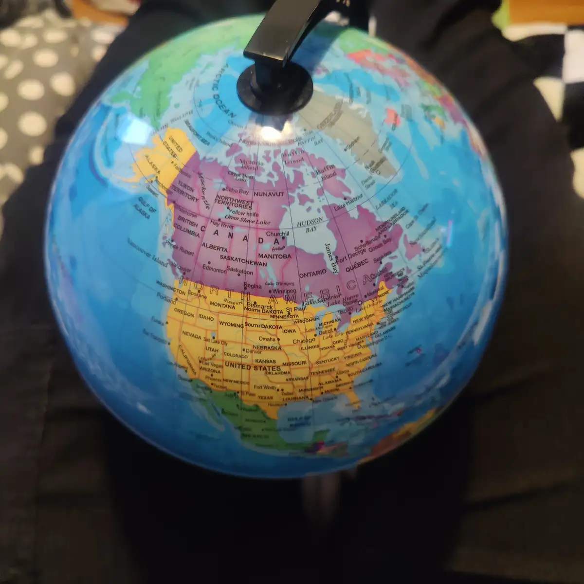 A close-up photo of a globe showing North America, with Canada and the United States clearly visible. The overlaid text…