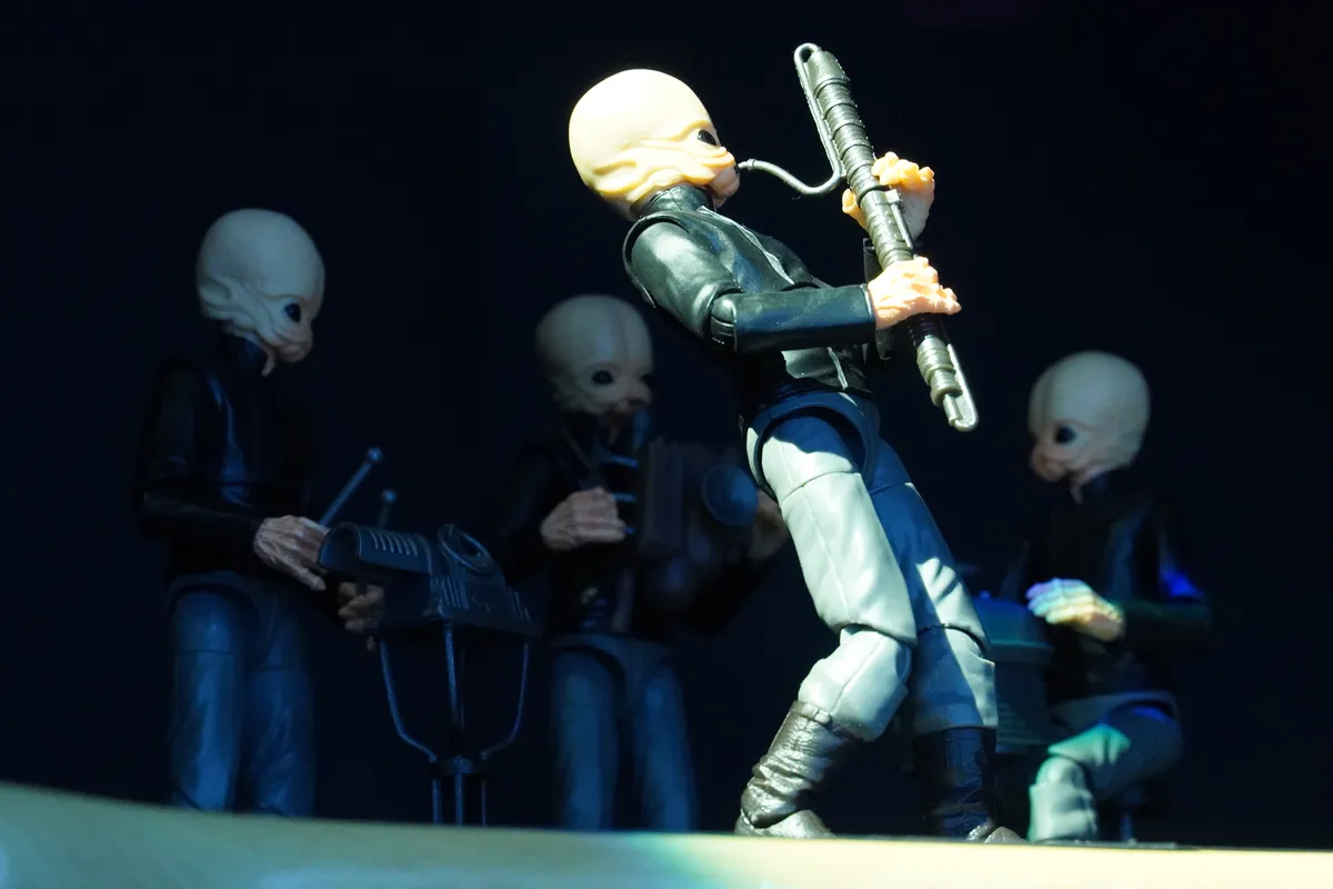 The image shows four action figures of alien characters resembling the Hutts from Star Wars, posed as if playing instruments…