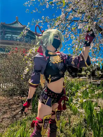 A person in a detailed cosplay of a video game character with light green hair, black face mask, and purple and gold armor…