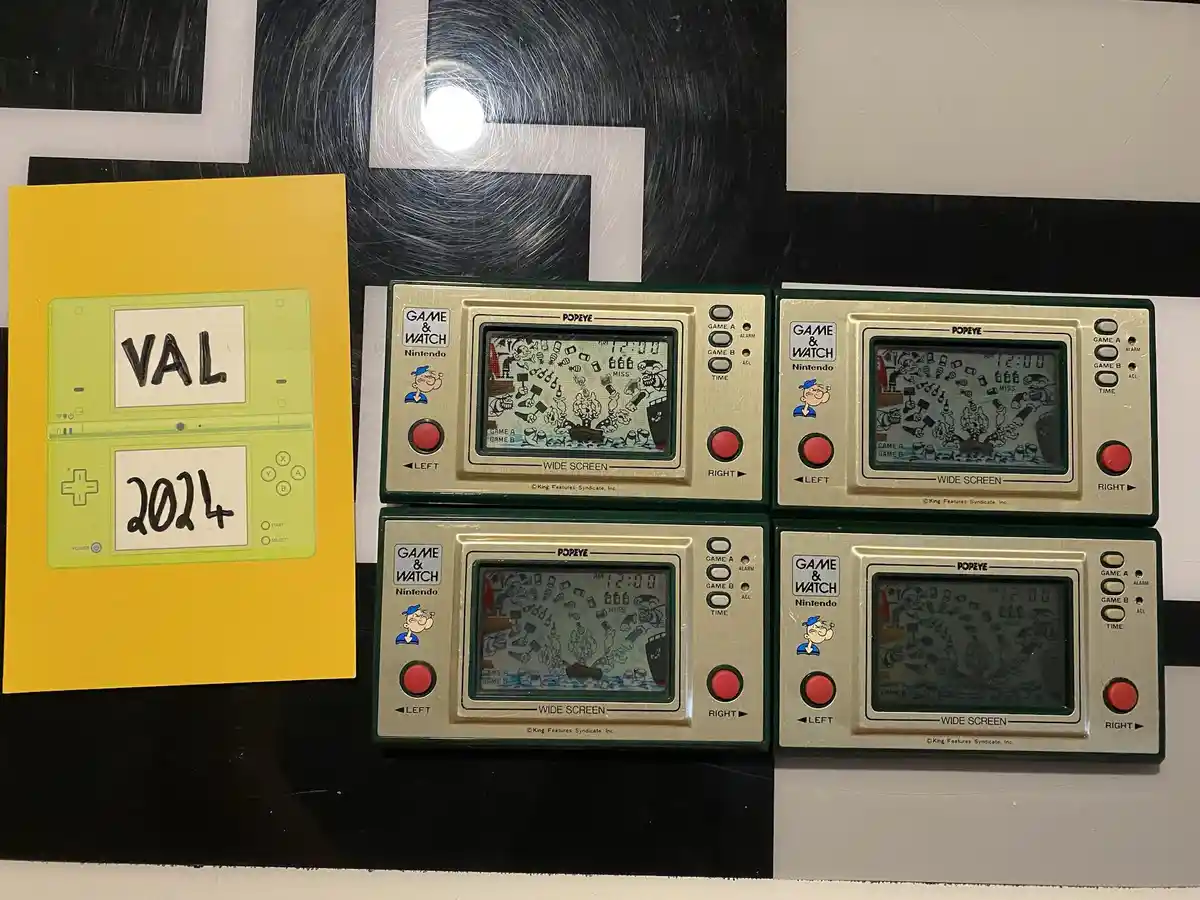 Four Nintendo Game & Watch Popeye handheld consoles are arranged in a 2x2 grid, each displaying the same Popeye game with a…