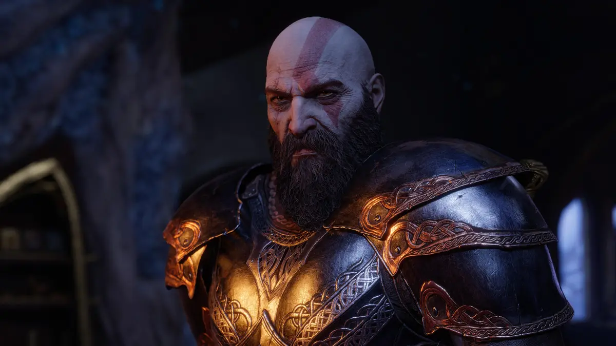 A close-up of the video game character Kratos from God of War, wearing ornate dark armor with gold trim, his face stern and…
