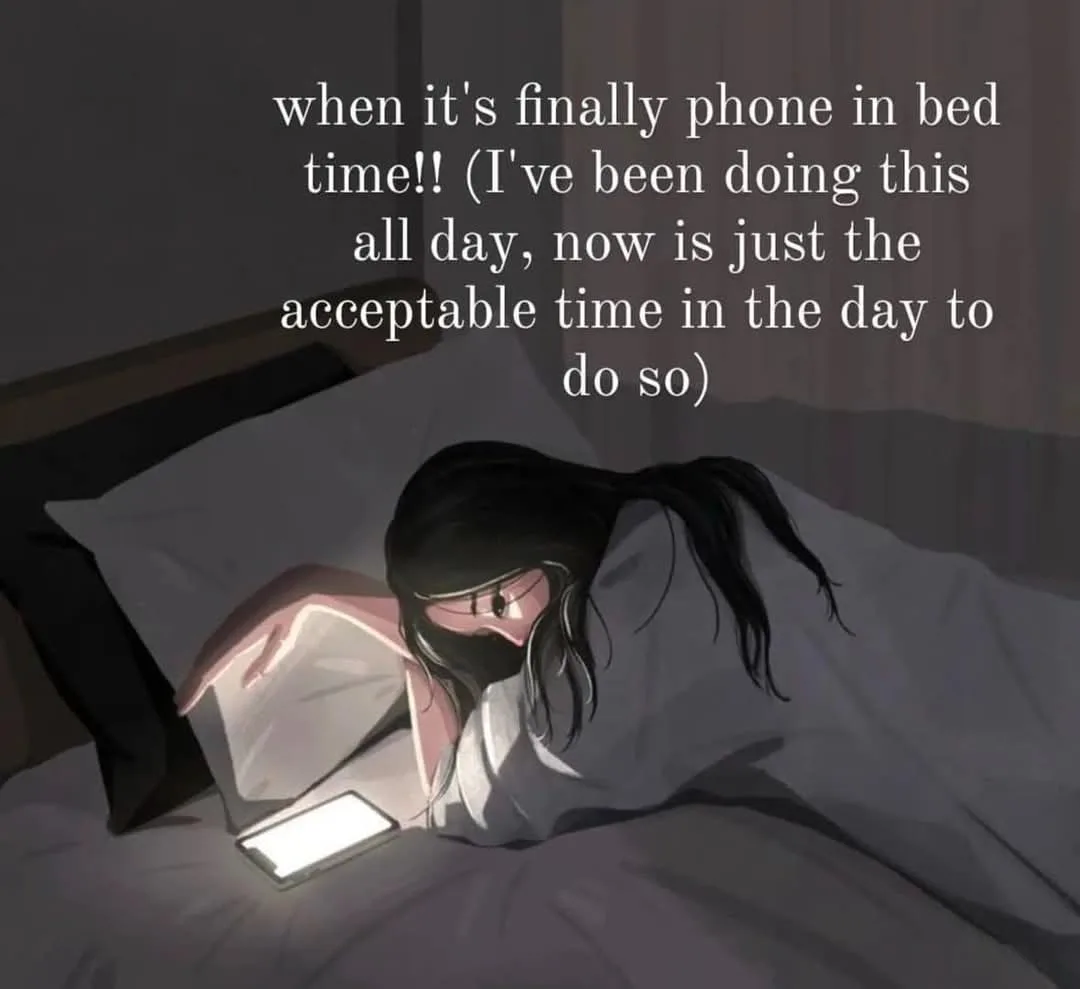 An anime-style illustration shows a person with long black hair lying in bed under gray blankets, illuminated by the glow of…