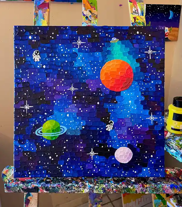 A textured, thickly painted canvas depicts a vibrant galaxy with a large orange planet, a green ringed planet, a pink moon…