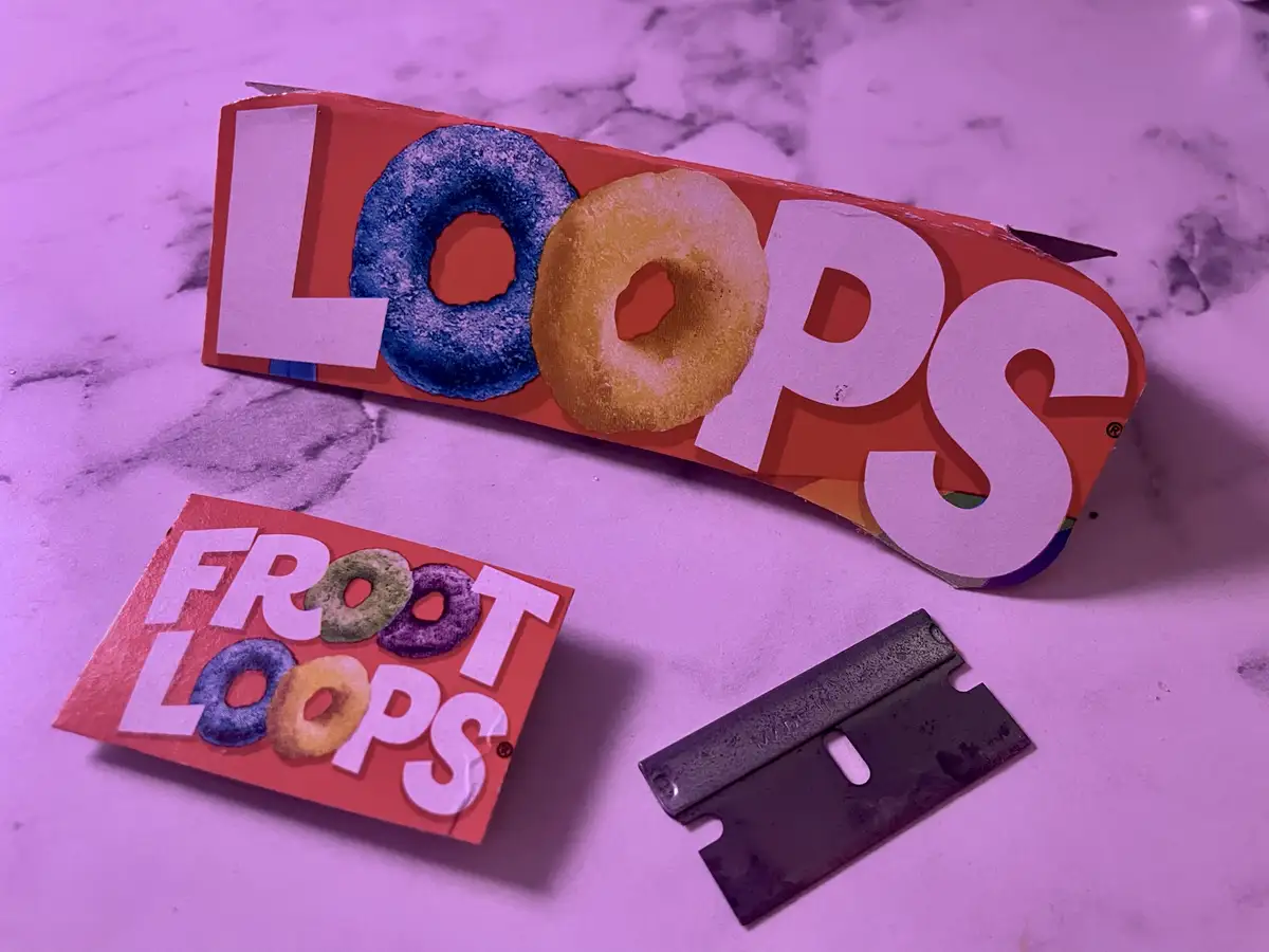 Two pieces of Froot Loops cereal box are shown on a purple-lit marble surface, one with the word 'LOOPS' and the other with…