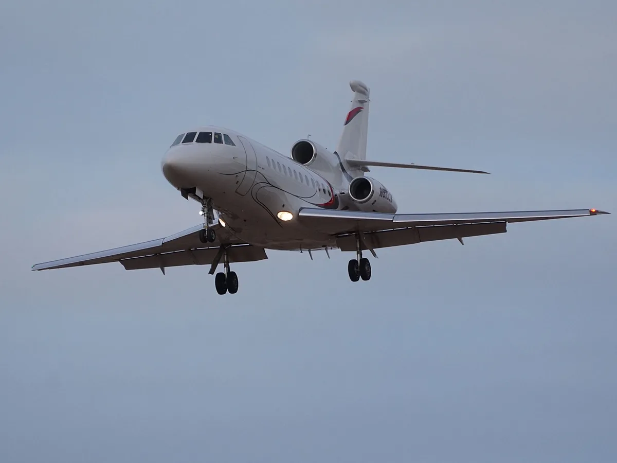 A white private jet with landing gear down and lights on is flying against a pale sky. The overlaid text reads 'i'm not…