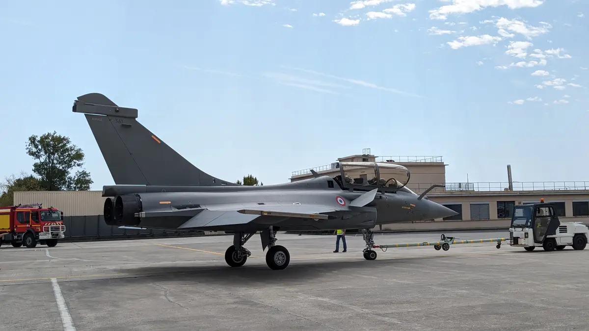 A grey French Dassault Rafale fighter jet, marked with 'RAFALE 361' on its tail, is parked on an airfield tarmac. Ground…