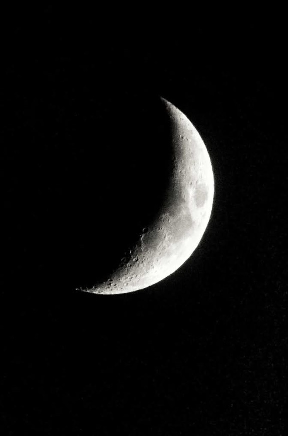A black and white photo shows a crescent moon against a dark sky, with visible craters and surface details. Overlaid text…