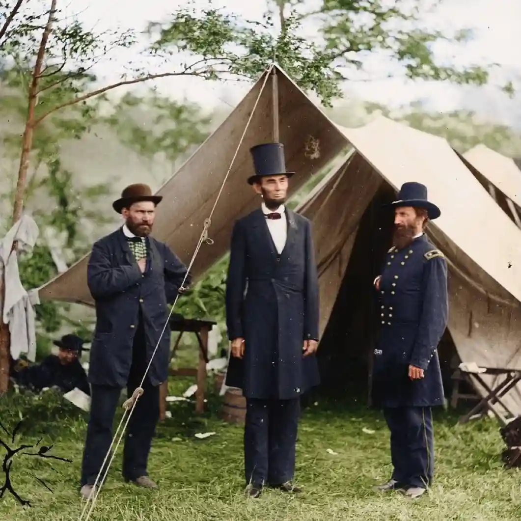 Three men in 19th-century attire stand outdoors near a canvas tent; the central figure, resembling Abraham Lincoln, wears a…