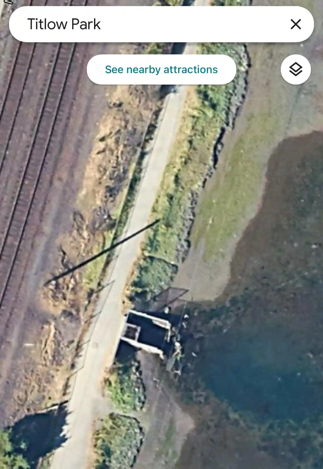 An aerial satellite view from Google Maps shows a search bar with 'Titlow Park' entered, revealing a rural landscape with a…