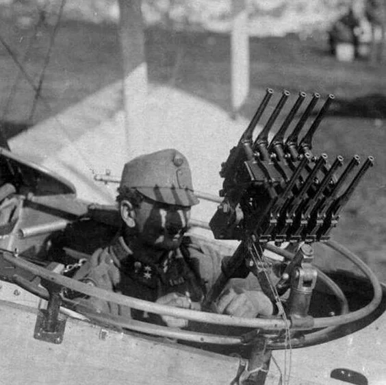 A black-and-white historical photo shows a soldier in a military aircraft cockpit, looking toward the camera with a stern…