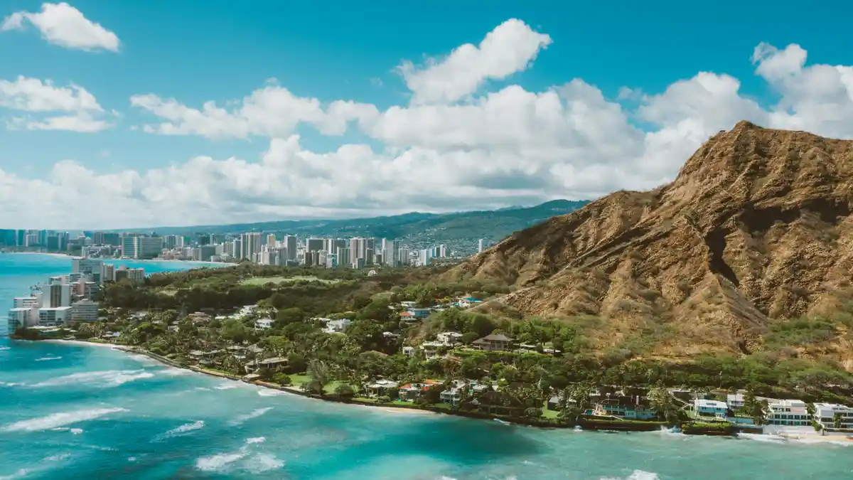 Vibrant hues of turquoise and emerald dance across the coastline as Diamond Head's ancient crater rises majestically from…
