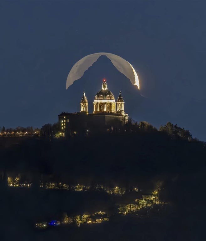 a night photograph shows a large, illuminated crescent moon positioned directly behind a mountain peak, creating the…