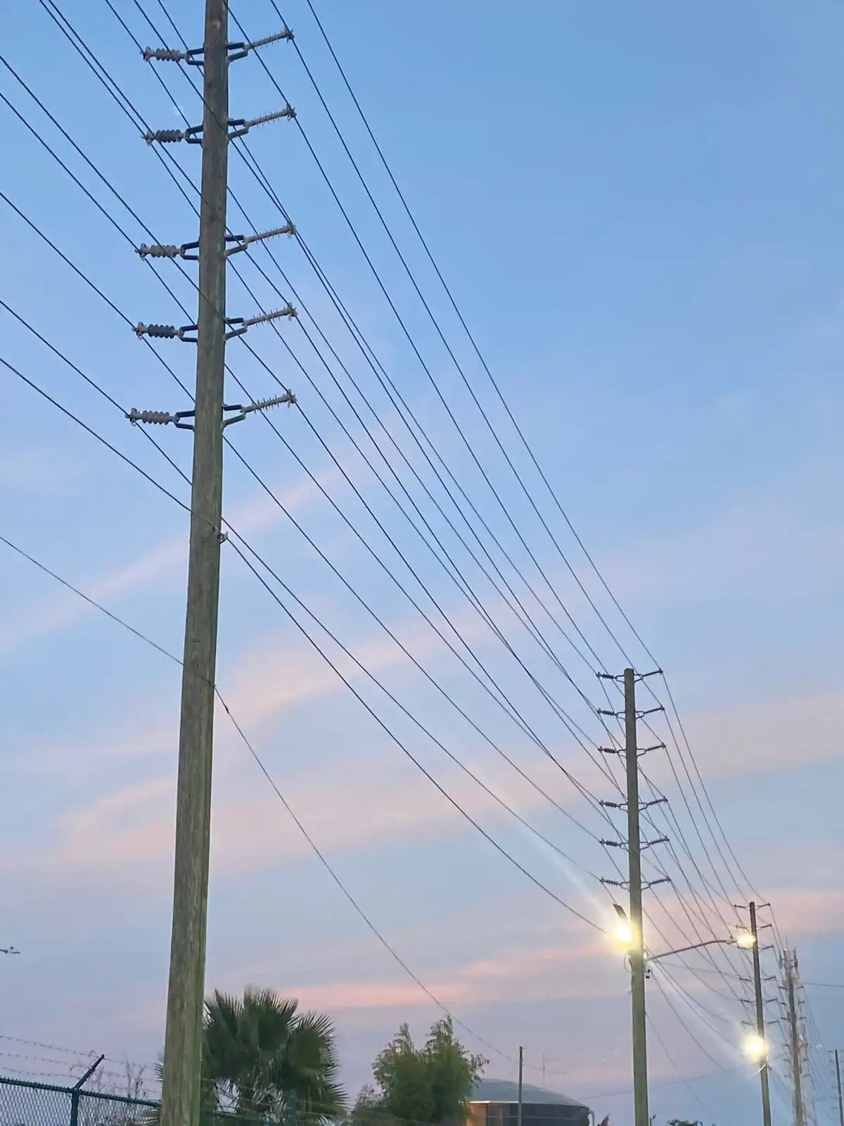 A photo of utility poles with power lines against a twilight sky, featuring streetlights glowing. Overlaid text reads 'i'm…